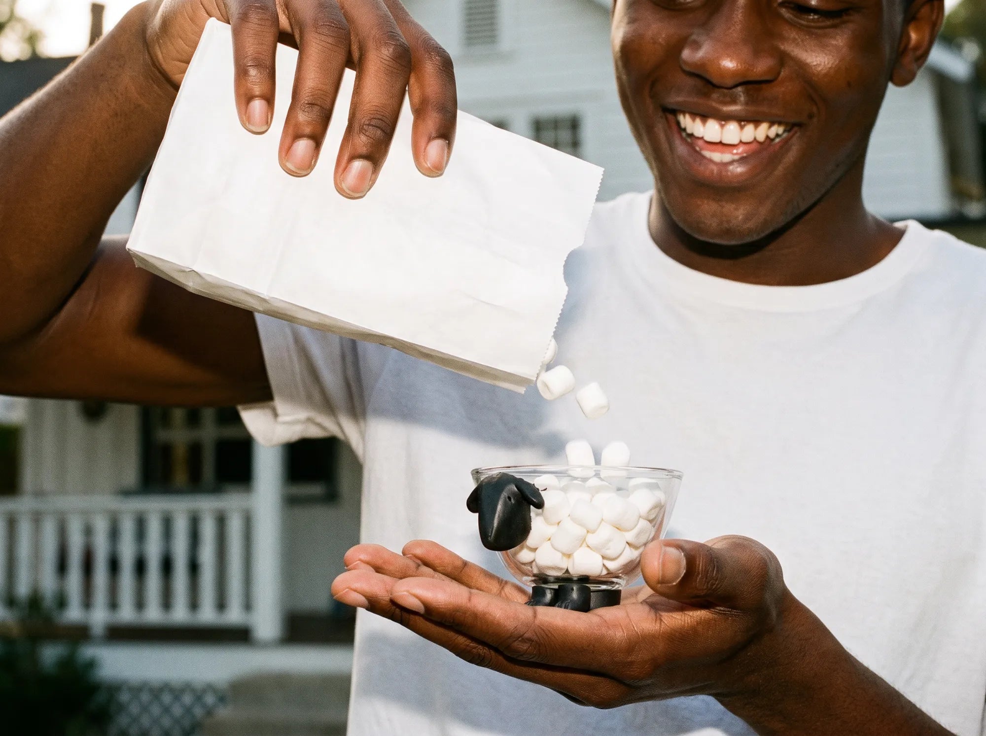Smiling young man pouring mini marshmallows into the Sheeply sheep glass bowl